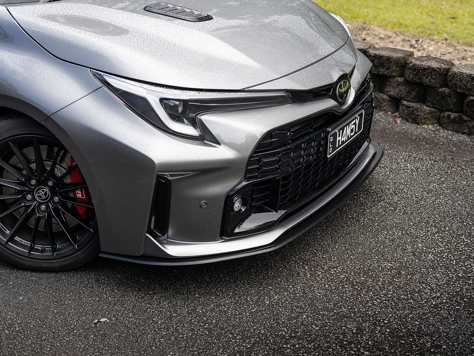 Angled side shot of GR Corolla front lip in satin black finish.