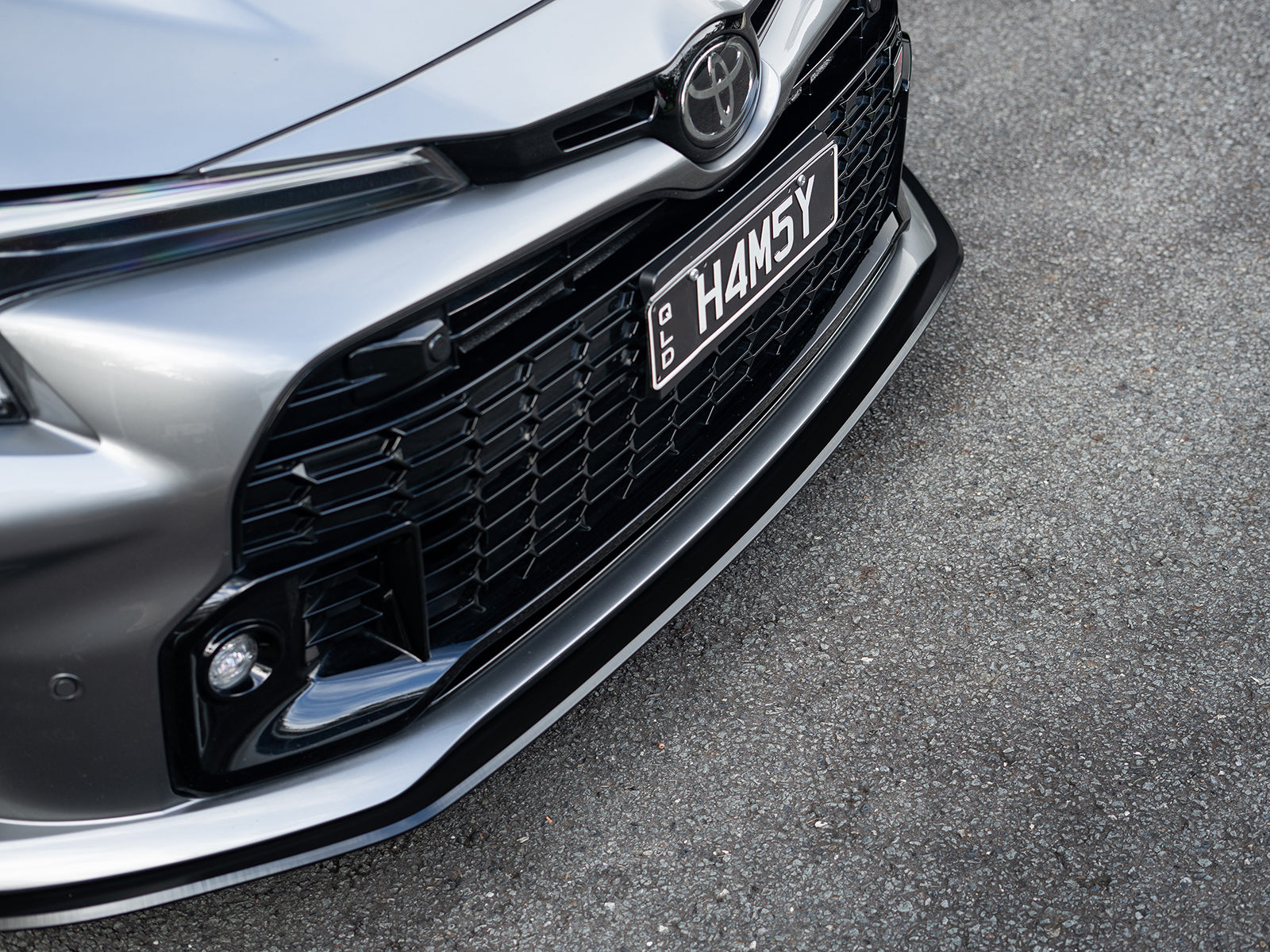 Close-up of the GR Corolla front lip splitter detail, highlighting clean fitment.
